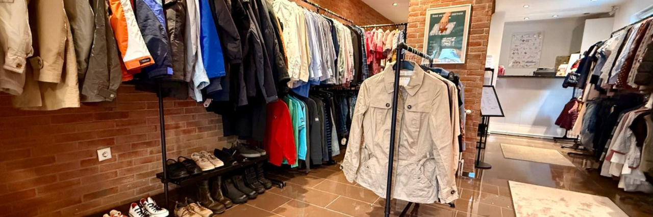 Kleiderladen Bad Soden Stage Image Der Raum vom VielfachSchön Bad Soden mit vielen Kleiderstangen mit Klamotten. Mittig ist eine Säule in Backstein-Optik zu sehen. Im Hintergrund ist ein Verkaufstisch.