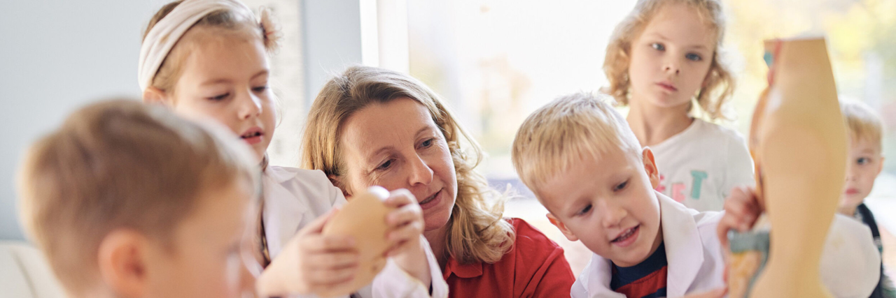 EH_am_Kind Mitarbeiterin des DRK zeigt einer Gruppe Kinder die menschlichen Organe am Beispiel eines Torsos. Die Kinder schauen neugierig zu.
