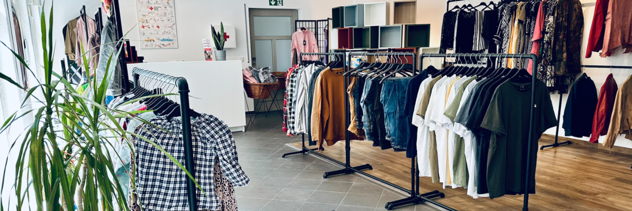 Kleiderladen Hochheim Stage Image Innenbereich vom VielfachSchön in Hochheim. Die Kleiderstangen stehen in einem ordentlichen, hellen Raum, in dem eine Pflanze steht.