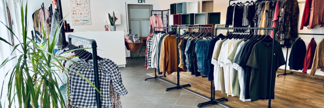 Kleiderladen Hochheim Stage Image Innenbereich vom VielfachSchön in Hochheim. Die Kleiderstangen stehen in einem ordentlichen, hellen Raum, in dem eine Pflanze steht.