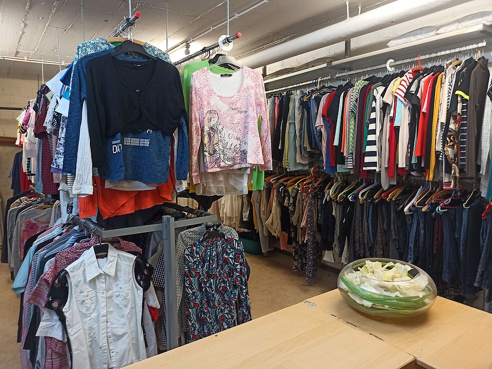 Kleiderkammer_Hofheim_Content_Image Ein Raum der Kleiderkammer mit vielen Kleiderstangen voller Kleidung.