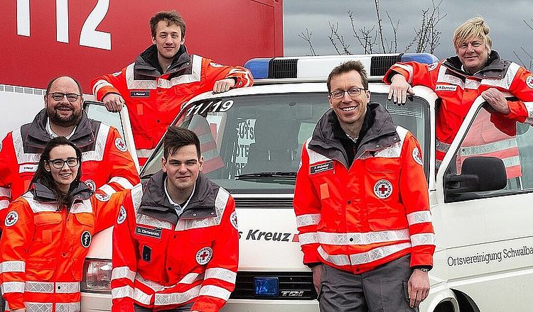 Schwalbach content img Sechs Personen in DRK Kleidung stehen um ein Einsatzfahrzeug herum. Zwei stehen in den Türen des Fahrzeuges, die restlichen Personen stehen davor.