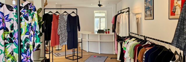 Kleiderladen Hofheim Stage Image Innenansicht vom VielfachSchön Hofheim: ordentlicher, heller Raum. Ausgestattet mit vielen Kleiderstangen. Im Hintergrund ein weißer Tresen.