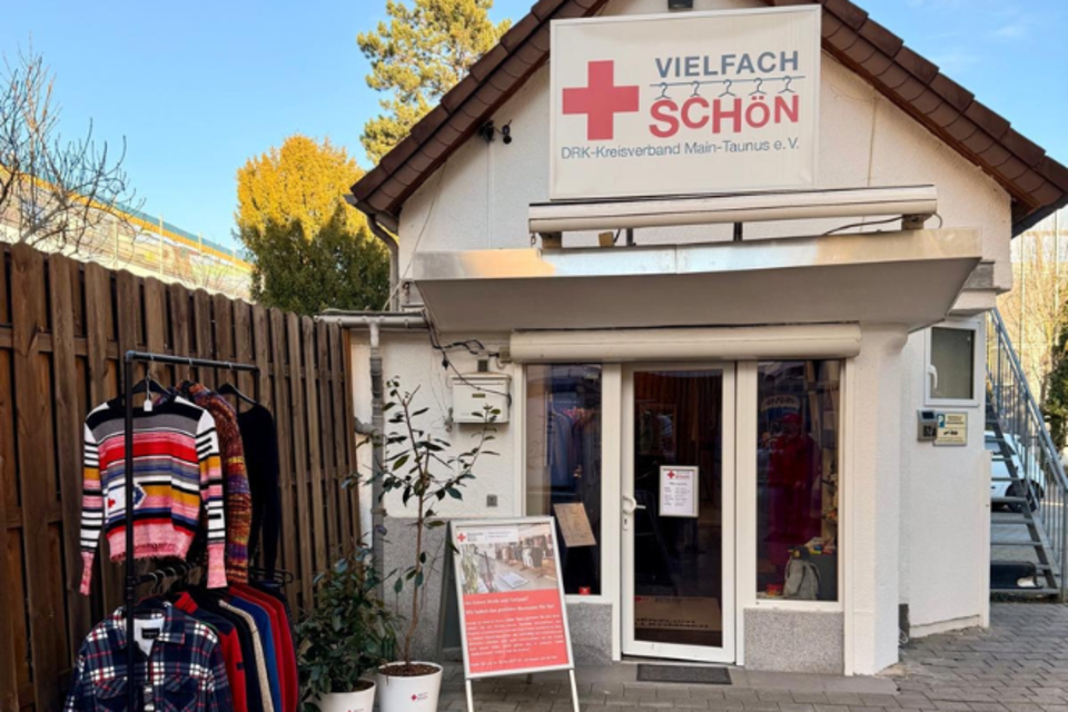 Kleiderladen Bad Soden Außenansicht vom VielfachSchön in Bad Soden. Ein kleines Haus in einem Hinterhof. Draußen ist eine Kleiderstange mit Kleidung und ein DRK-Plakat aufgestellt.
