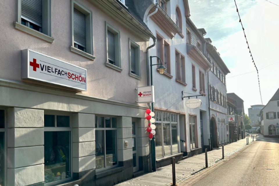 Kleiderladen Hochheim Außen Außenansicht vom VielfachSchön in Hochheim. Inmitten der Häuser der Altstadt ist das Schild des DRK-Ladens zu sehen, blaue und weiße Luftballons hängen neben dem Eingang.